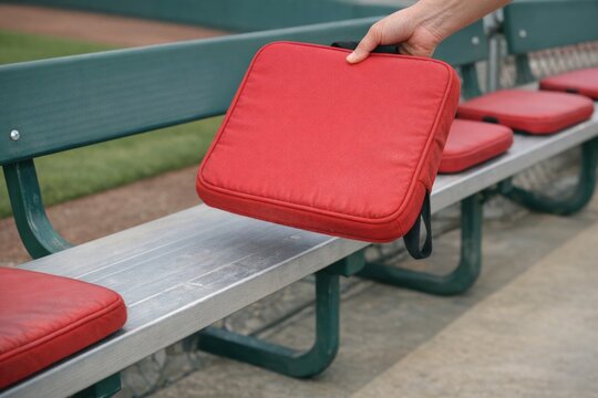 A person sitting on a bench holding a red piece of luggage, possibly waiting for someone or something