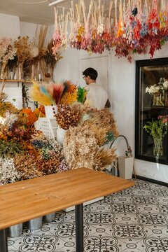 Young male florist walking away in a colorful flower shop
