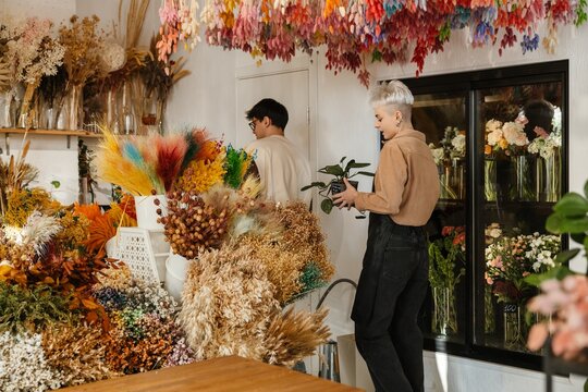 Two young florists holding plant in a colorful flower shop