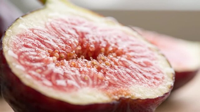 Sliced fig reveals glistening seeds and rich pink juicy pulp inside.