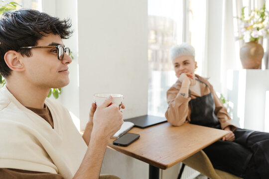 Two young florists drinking coffee in a colorful flower shop