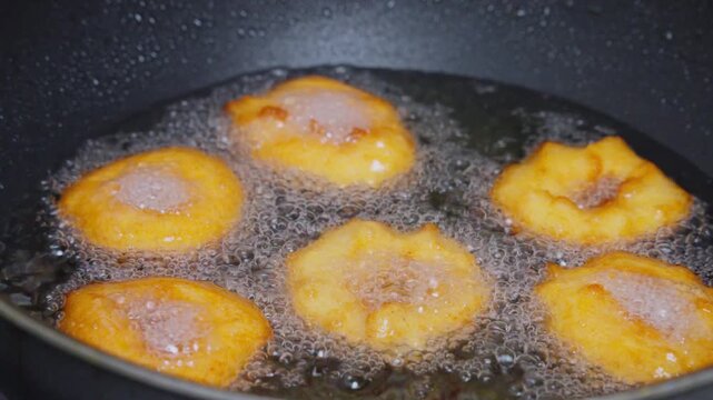 Crispy medu vada frying to golden brown in bubbling hot oil during festival