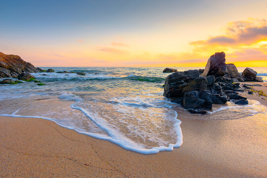 sea beach at sunrise. Bulgaria summer vacation background. colorful sky with glowing clouds. waves, sand and rocks in morning light