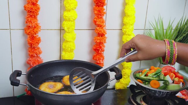 Cook frying medu vada in a kadai with a slotted spoon during Diwali festival