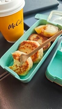 Gdansk, Poland - July 22, 2026: McDonald's McCafe coffee cup beside a green food container with potato pancakes and fruit pieces on a table