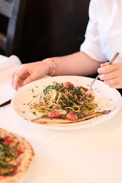 Frau sitzt als Gast im Restaurant und isst eine Speise Pasta