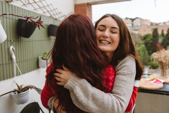 Two female friends hugging someone during a birthday celebration