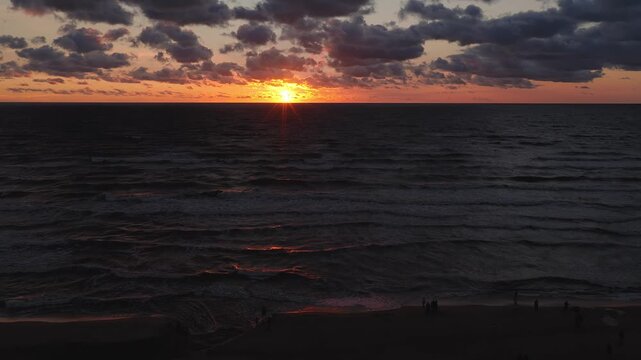 Aerial view of the solar eclipse of 2026 during sunset time with the sun mostly covered by the moon over the ocean and dark waves on the beach.
