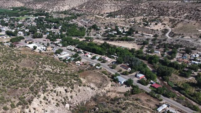 Aerial of small desert townscape and residential area in Naturita Colorado with scrubland hillsides and dirt roads and desert bluffs