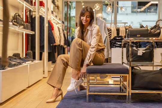 Young pretty woman trying on new shoes in a fashionable boutique