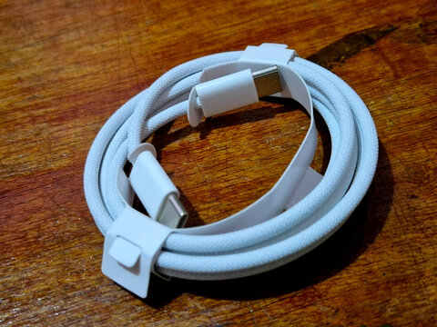 Coiled white braided USB Type-C cable on wooden table.