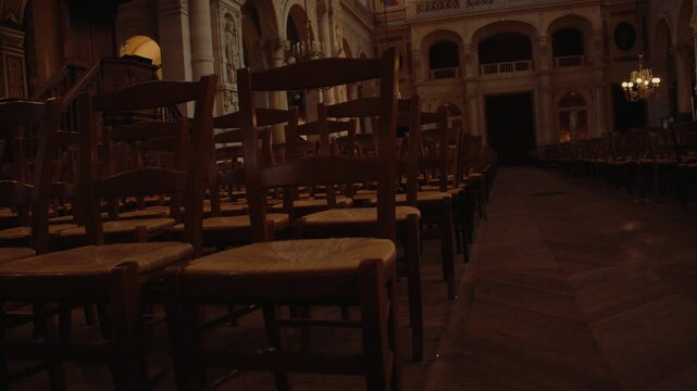 Rows of wooden church chairs arranged inside dim historic sanctuary with ornate architecture and traditional interior design