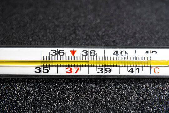 Mercury thermometer  on black background. Close up photo. Thermometer shows a temperature of 38 degrees Celsius