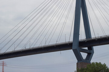 Fototapeta premium Modern cable-stayed bridge with steel cables and concrete supports against a cloudy sky, showcasing architectural design and engineering in an urban landscape