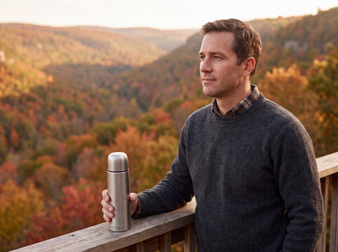 Man with thermos at autumn mountain overlook and valley view