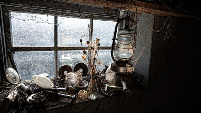 A dramatic still life by the window. A creative workshop of vintage interiors. A kerosene lamp in a dark barn. A floral arrangement in a still life.Light in the window. 