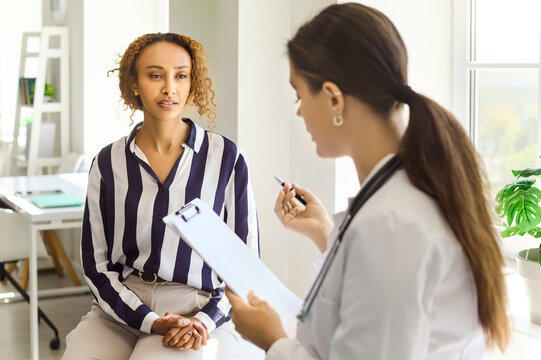 Doctor and patient consultation in clinic healthcare. Female doctor holds clipboard and pen discussing symptoms and next steps at appointment. Concept medical consultation and patient care.