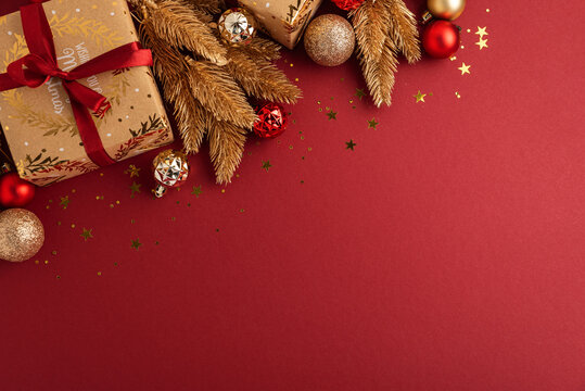 Festive Christmas Decorations and Presents on Red Background with Golden Sparkles and Fir Branches