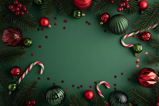 Festive Christmas border with ornaments pine branches and candy canes on dark green background