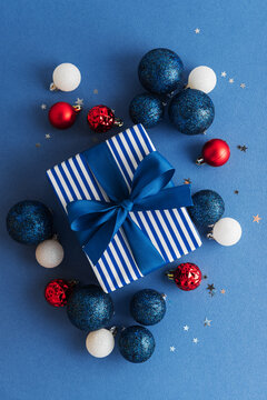 Festive Blue White Gift Box Wrapped Ribbon Surrounded By Christmas Baubles And Confetti