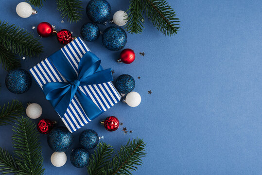 Festive Christmas Gift Box With Ornaments And Pine Branches On Blue Background