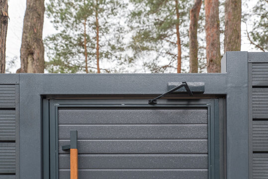 Outdoor hydraulic door closer on anthracite metal gate with wooden handle