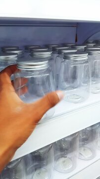 Close-up of a person holding an empty clear plastic jar with a metallic lid