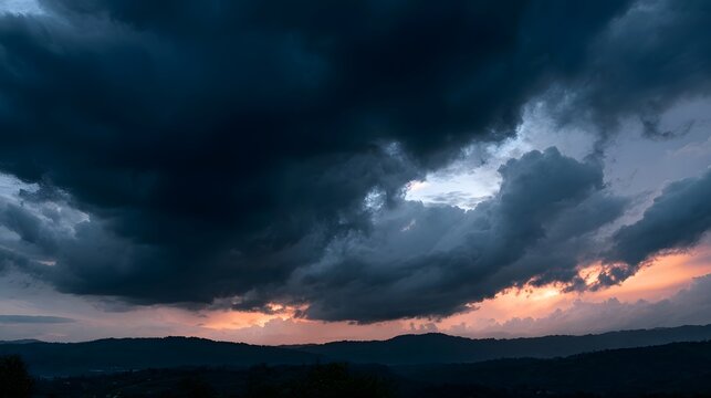 Dramatic storm clouds gather over rolling hills at twilight  casting deep shadows and glowing orange light along the horizon
