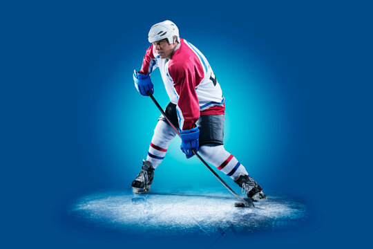 Hockey. Professional hockey player isolated on blue background. Hockey player in action. Hockey concept. Sport