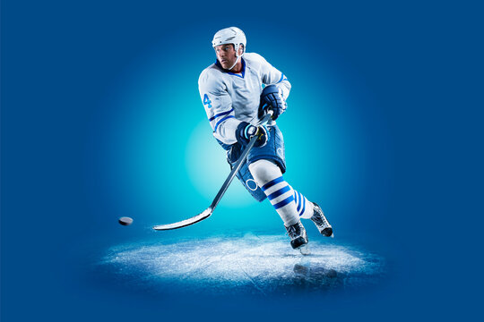 Hockey. Professional hockey player isolated on blue background. Hockey player in action. Hockey concept. Sport