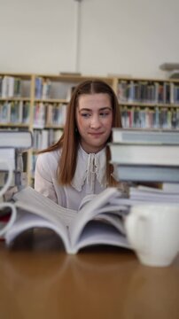 Vertical screen young woman smiles skeptically while reading a book in library doubting the information and questioning whether the written content can really be trusted