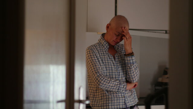 Female cancer patient standing alone in kitchen during recovery journey, highlighting emotional strain, resilience, uncertainty, reflection and personal strength