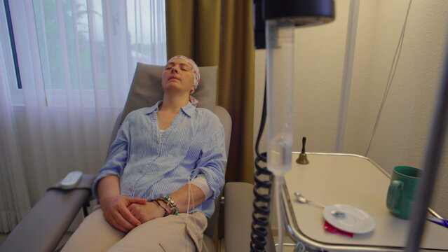 Medical infusion drip and female patient in treatment chair at healthcare clinic, focus shifting between equipment and patient to symbolize healing, resilience and recovery