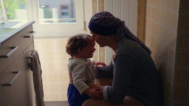 Mother embracing upset toddler while offering comfort and emotional support, authentic family lifestyle scene highlighting secure attachment, affection and parental care