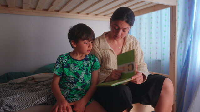 Mother explaining storybook content to son during shared reading activity creating supportive learning environment focused on literacy language and childhood education