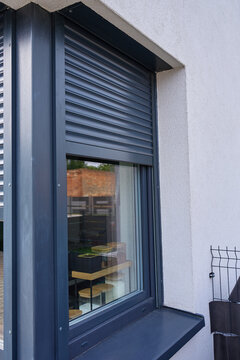 Roller shutter partly covers kitchen window set in exterior wall, with storage jars visible inside