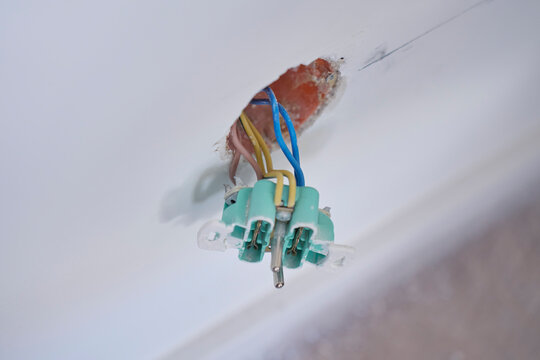 Electrical wires and socket mechanism exposed through an opening in plaster wall