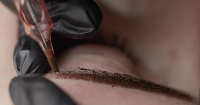 Slow motion close up cosmetic eyebrow microblading procedure on skin in beauty studio, Macro permanent makeup.