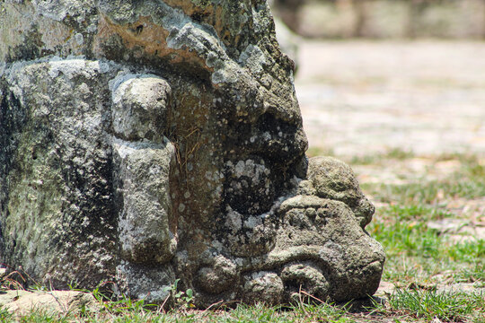 close-up of weathered zoomorphic stone monument covered in moss on grass background