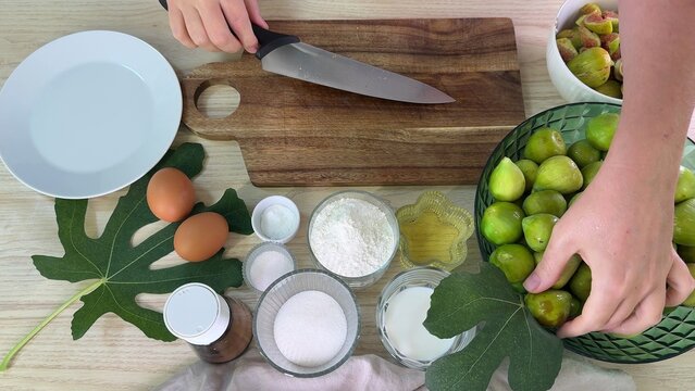 A close up view of fresh green leaves and herbs on a rustic wooden cutting board surface, perfect for cooking preparations or culinary inspiration shots, vibrant natural colors