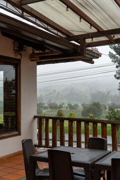 Terraza de madera con mesa y sillas vista al paisaje monta&ntilde;oso con niebla de Boyac&aacute;