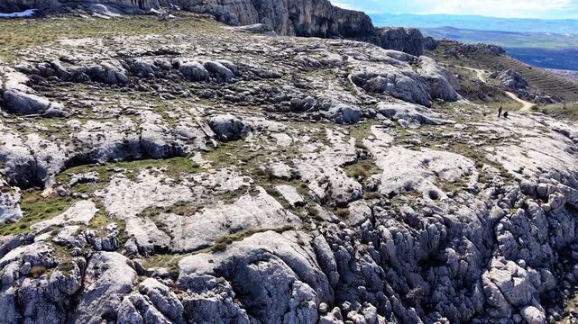 Fast smooth aerial movement to the right while advancing and descending toward a dramatic rock formation, revealing rugged cliffs and natural cave formations.
