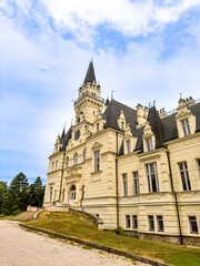 Historic Budmerice Manor castle facade under cloudy blue sky. Low angle exterior view of yellow palace building with clock tower in Slovakia. © Анна Терелюк