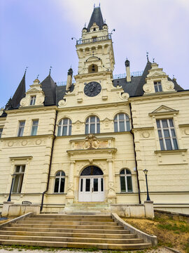 Historic building with intricate design. The photo shows a large historic building with a clock on its facade. Steps lead up to the front doors.