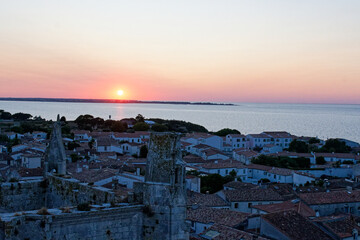 Saint-Martin-de-Ré au coucher du soleil offre un spectacle magique, où la lumière dorée illumine les fortifications de Vauban, le vieux port et les reflets paisibles de l'océan. © bru greg