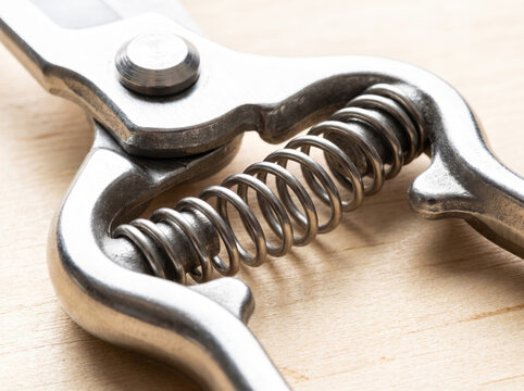 Close up of metal secateurs spring mechanism on a wooden background