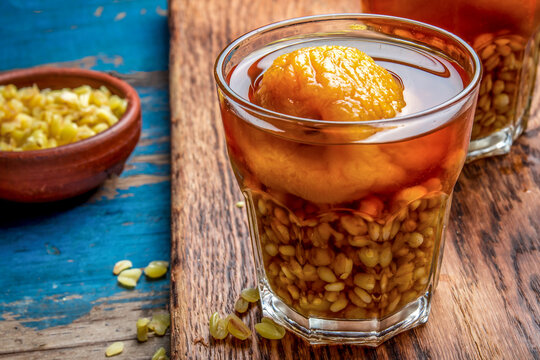 Mote con huesillo. Traditional Chilean drink made from cooked husked wheat and dried peach on wooden board, rustic blue background