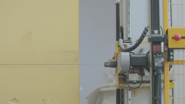 A close-up of a large polyurethane foam block being cut on a CNC machine. Automated CNC foam cutting machine processing a large block of polyurethane foam in a modern factory setting. 