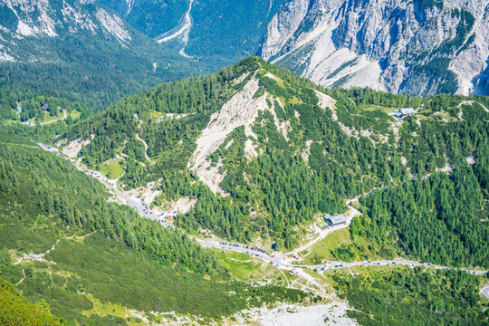 Vrsic Pass shows a winding road through green forests and rocky mountains in Slovenia. This high road is a start for many hiking paths at a popular outdoor location.