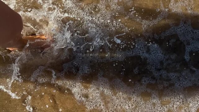 Woman walking from sea onto sandy beach. 4k